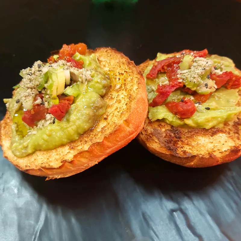 Avocado toast topped with tomatoes and greens.