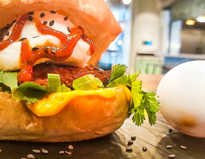 A breakfast bun filled with egg, cheese, tomato and greens.