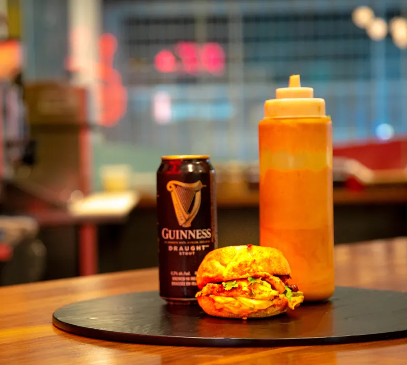 A chicken sandwich and cold drinks on a café table.