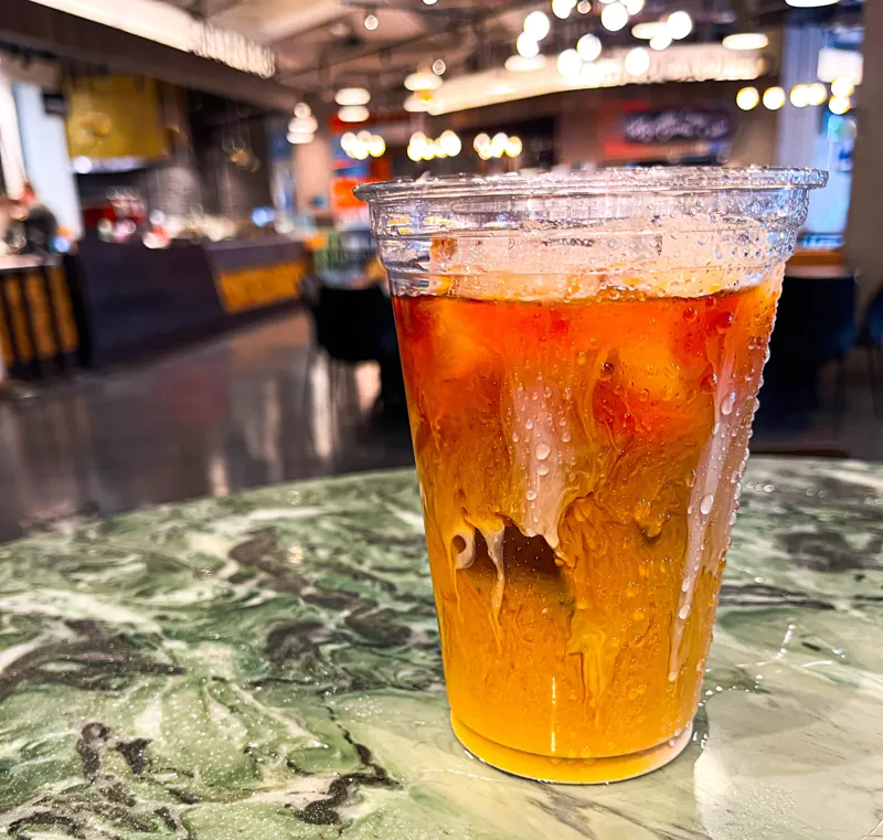 A tall amber drink filled with ice at the bar.