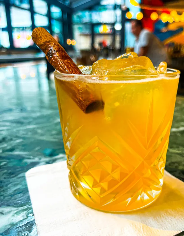 An orange cocktail garnished with a twist of citrus.