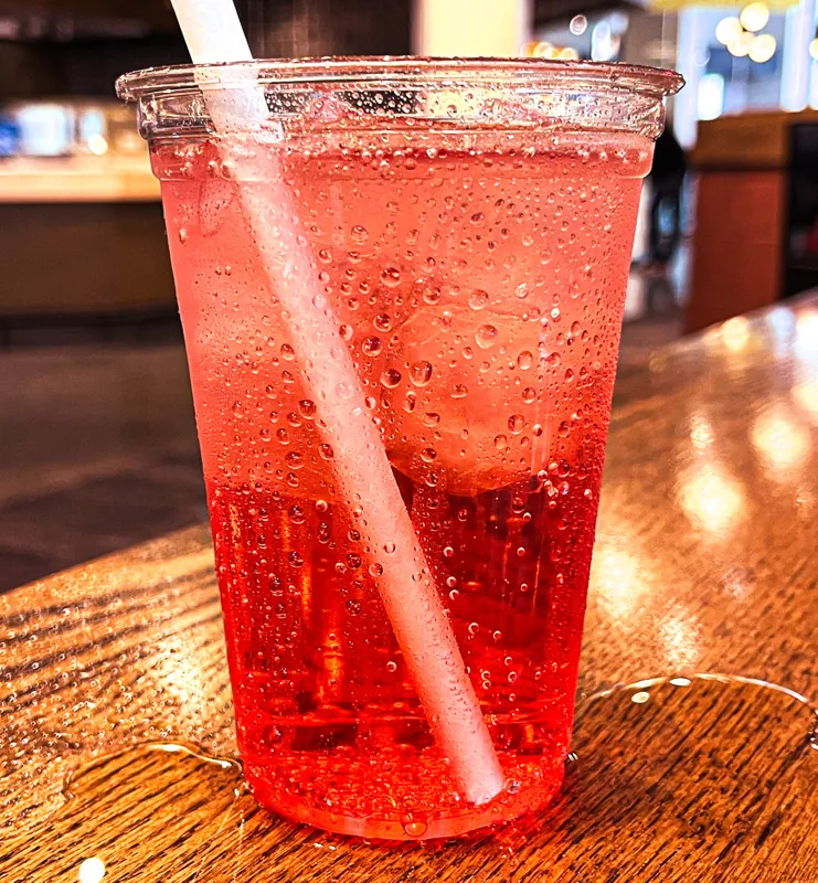 A tall red iced drink on the marble counter.