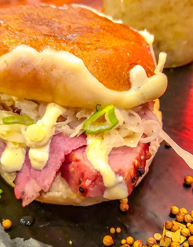 A toasted sandwich filled with sliced meat and melted cheese.
